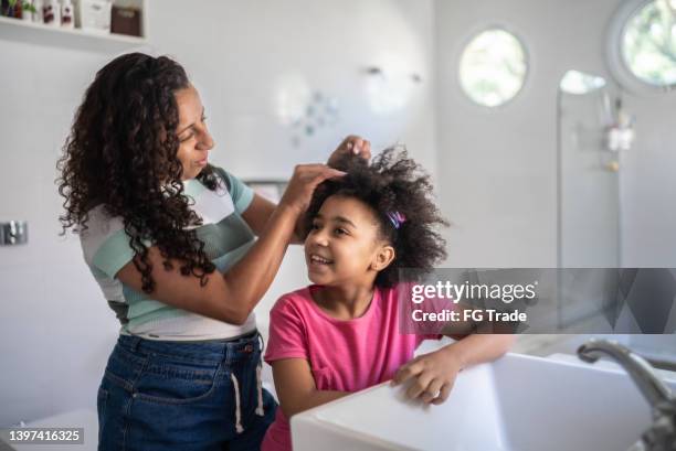 mother combing daughter's hair at home - candid curly hair stock pictures, royalty-free photos & images