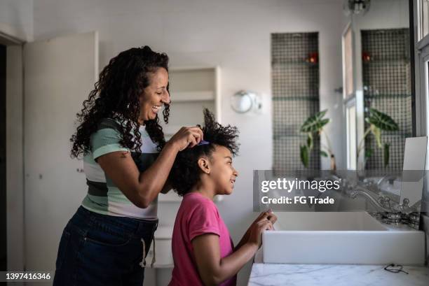 mother combing daughter's hair at home - hair care bildbanksfoton och bilder