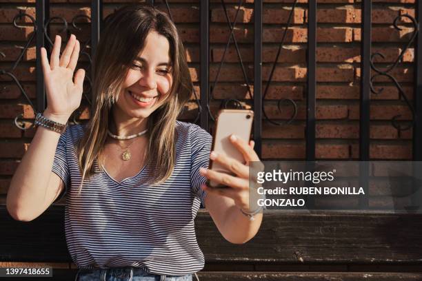 smiling young caucasian woman with using mobile phone and greeting a friend. - teen webcam foto e immagini stock