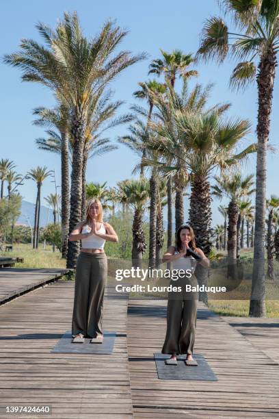 two women meditating in the park - benicassim stock-fotos und bilder