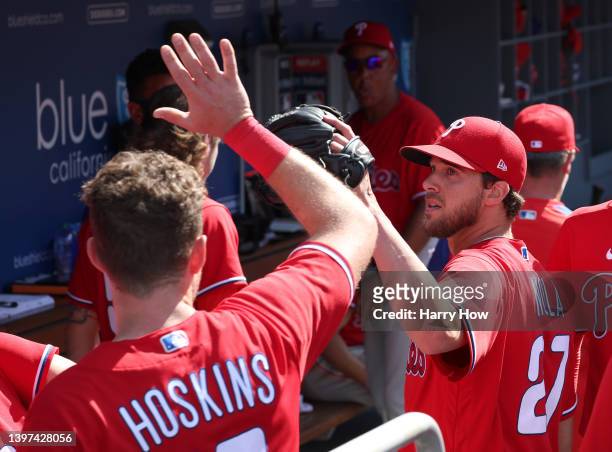 Aaron Nola of the Philadelphia Phillies gets a high five from Rhys Hoskins as he comes into the dugout after the third out of the seventh inning...