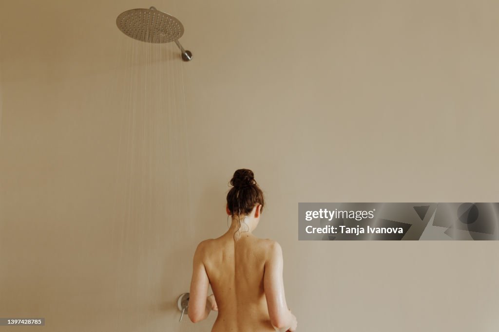 Rear view of young attractive woman taking shower