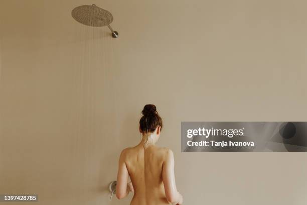 rear view of young attractive woman taking shower - woman body stockfoto's en -beelden