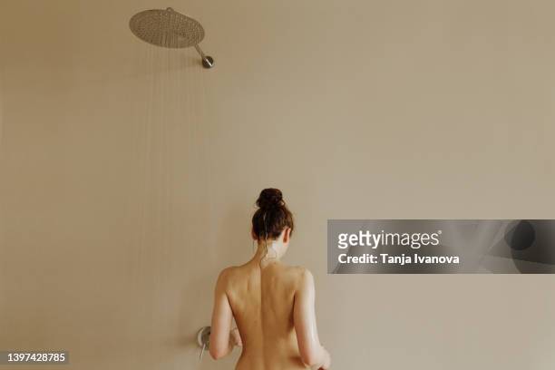 rear view of young attractive woman taking shower - women taking showers stock pictures, royalty-free photos & images