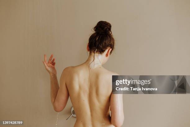 rear view of young attractive woman taking shower - back body stock pictures, royalty-free photos & images