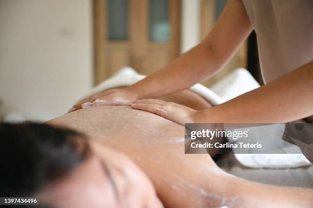 woman receiving a body scrub in a luxury spa - parte del corpo foto e immagini stock
