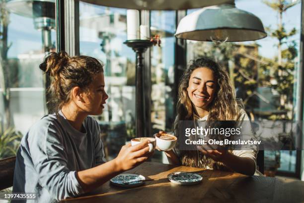 two people in cafe. cheerful young woman blogger showing content on smartphone - coffee meeting with friends imagens e fotografias de stock
