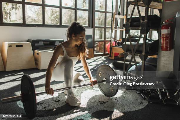 woman holding grip of barbell and ready to picking up it. women's weightlifting. beautiful morning light in gym - snatch weightlifting stockfoto's en -beelden