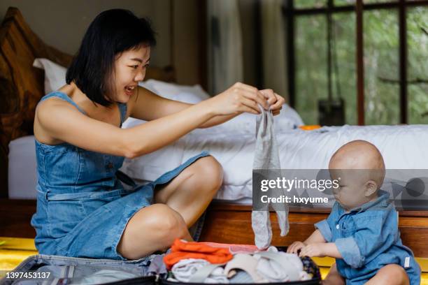 tourist mother and baby packing luggage for in bedroom - baby bag bildbanksfoton och bilder