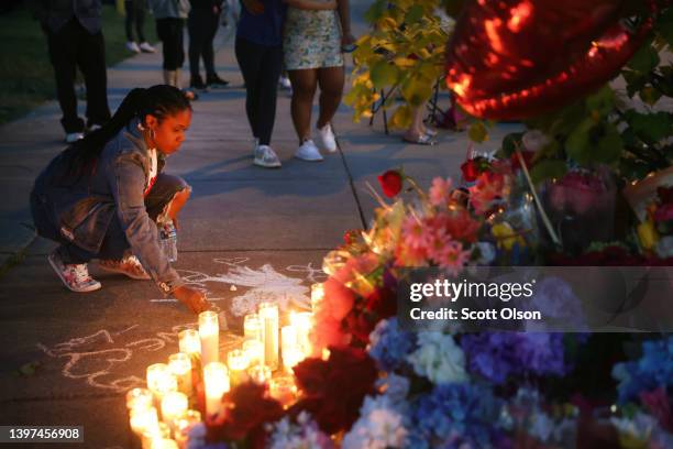 Woman chalks a message at a makeshift memorial outside of Tops market on May 15, 2022 in Buffalo, New York. A gunman opened fire at the store...