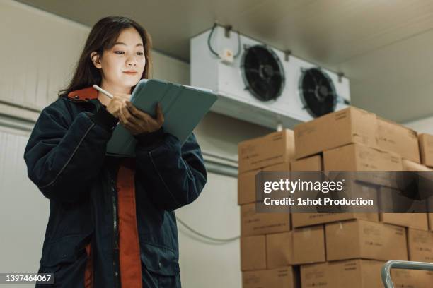 cold storage worker woman using digital tablet to check stock. - voedselveiligheid stockfoto's en -beelden