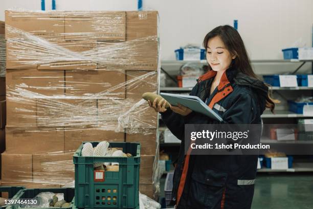 cold storage worker woman using digital tablet to check stock. - winkelketen stockfoto's en -beelden
