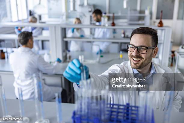happy male scientist taking test tube in a laboratory. - choosing experiment stockfoto's en -beelden