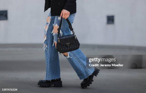 Tuana Koc is seen wearing a black blazer, a black top, a blue denim with cut outs, black loafer and a black Guess mini leather handbag and sunglass...