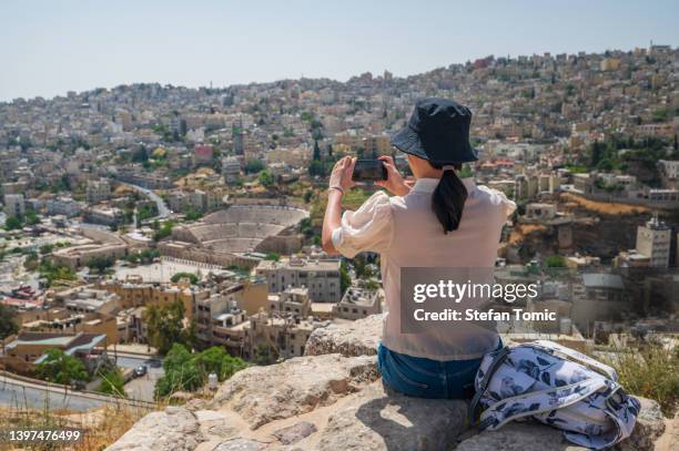 晴れた日に旧市街のスカイラインを見下ろす写真を撮るヨルダンのアンマンを訪れる女性 - アンマン市 ストックフォトと画像