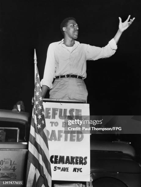 American civil rights activist Bayard Rustin speaking at a Peacemakers meeting, at a lectern on which is written 'Refuse to be Drafted, Peacemakers,...