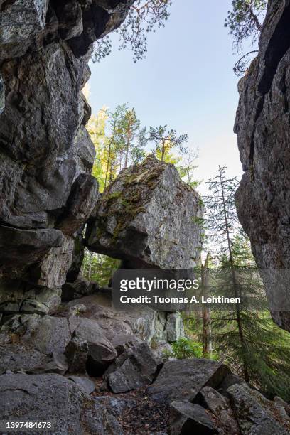 famous cave and cliff in a lush forest at the pirunvuori ("devil's mountain") on a sunny morning at summer in sastamala, southern finland. - southern finland stockfoto's en -beelden