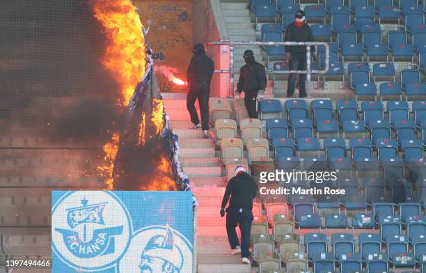 Masked people burn flags in the stands during the Second Bundesliga match between FC Hansa Rostock and Hamburger SV at Ostseestadion on May 15, 2022...