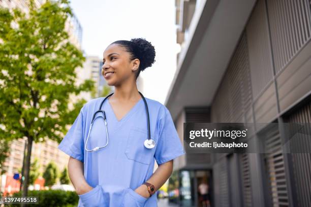 jeune infirmière colombienne confiante à l’extérieur qui détourne le regard avec le sourire aux lèvres. - infirmière photos et images de collection