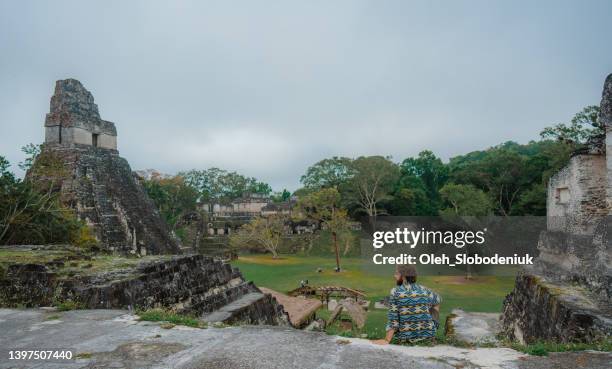 man sitting and looking at tikal national park - ruined stock pictures, royalty-free photos & images