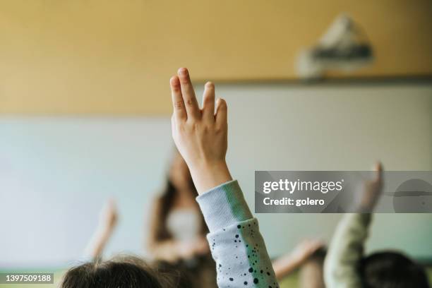 school girl in classroom putting up hand - girls hands behind back stock pictures, royalty-free photos & images