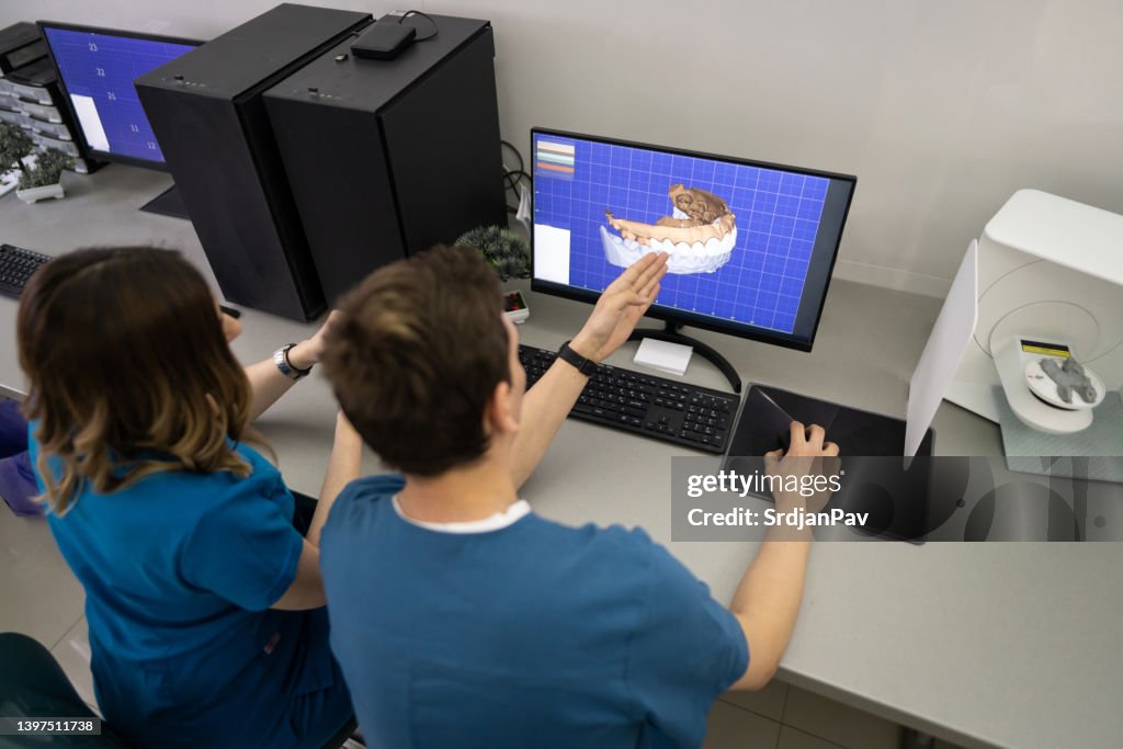 Männlicher und weiblicher Kollege, der das 3D-Kiefer- und Zahnmodell am Computer beobachtet