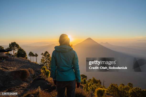 frau steht auf dem hintergrund des vulkans in guatemala - guatemala stock-fotos und bilder
