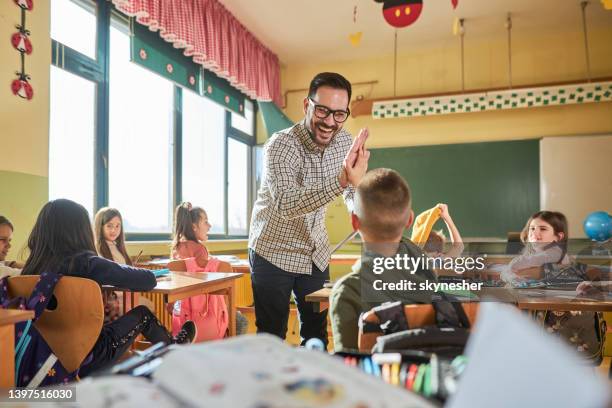 happy teacher and schoolboy giving each other high-five on a class. - congratulating child stock pictures, royalty-free photos & images