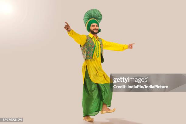 sikh man performing bhangra during baisakhi celebration - bhangra fotografías e imágenes de stock