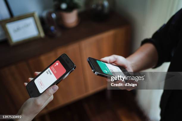 cropped shot of a man and a woman's hand holding smartphone, sending money through digital wallet, using online banking mobile app device. friends holding mobile phone to activate nfc. smart banking with technology - near field communication stock pictures, royalty-free photos & images