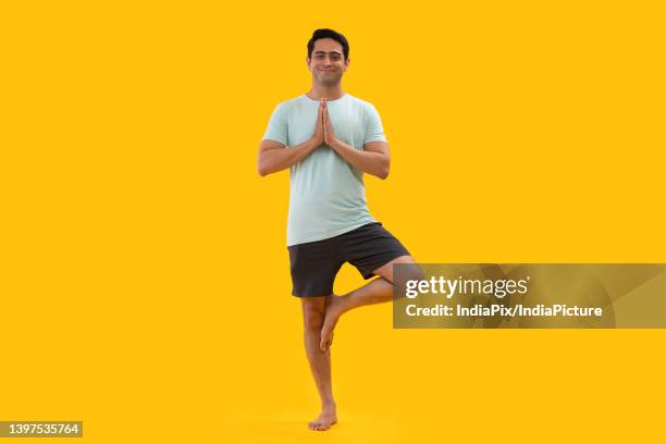 portrait of a young man practicing yoga - tree position stock pictures, royalty-free photos & images