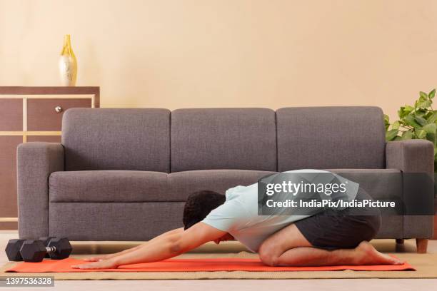 человек в позе ребенка на коврике для йоги