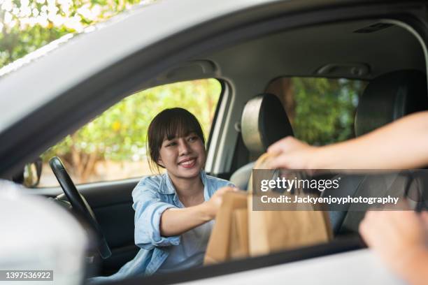 a young woman smiles as she picks up her curbside order in her car. - カーブサイドピックアップ ストックフォトと画像