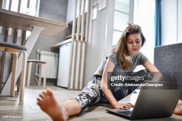 female athlete picking her exercises at home on laptop - maillot de sport stockfoto's en -beelden