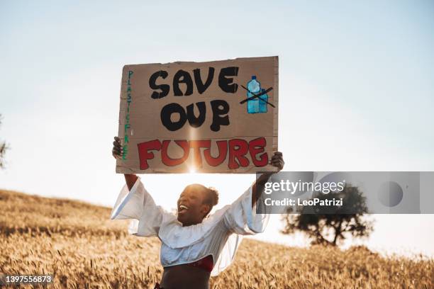 woman standing in nature with a message to raise awareness against climate change - plastic free stock pictures, royalty-free photos & images