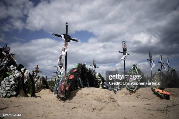 Crosses, floral tributes and photographs of the victims of the battles for Irpin and Bucha mark the graves in Irpin cemetery on May 16, 2022 in...