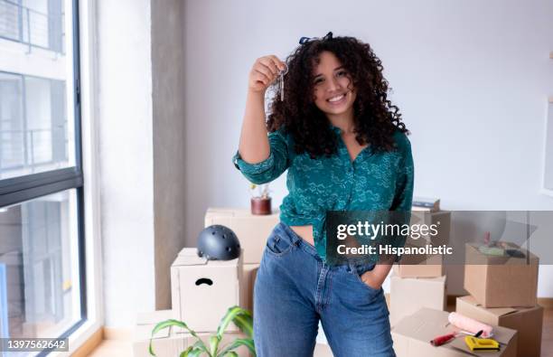 jovem linda mulher afro-americana segurando as chaves de sua nova casa enquanto enfrenta a câmera com um sorriso dentuço - chave - fotografias e filmes do acervo