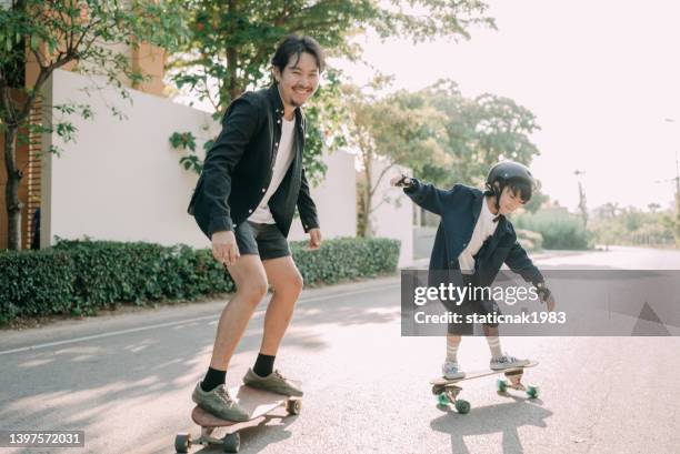 asian father and son skateboarder practicing in the public park. - father helping son wearing helmet stock pictures, royalty-free photos & images