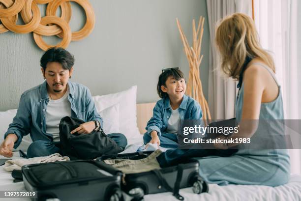 jeune voyageur en famille qui leur fait valise pour le prochain voyage. - carry on luggage photos et images de collection