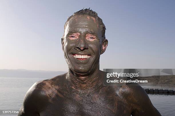 smiling man at the dead sea covered in mud. jordan - people covered in mud stock pictures, royalty-free photos & images
