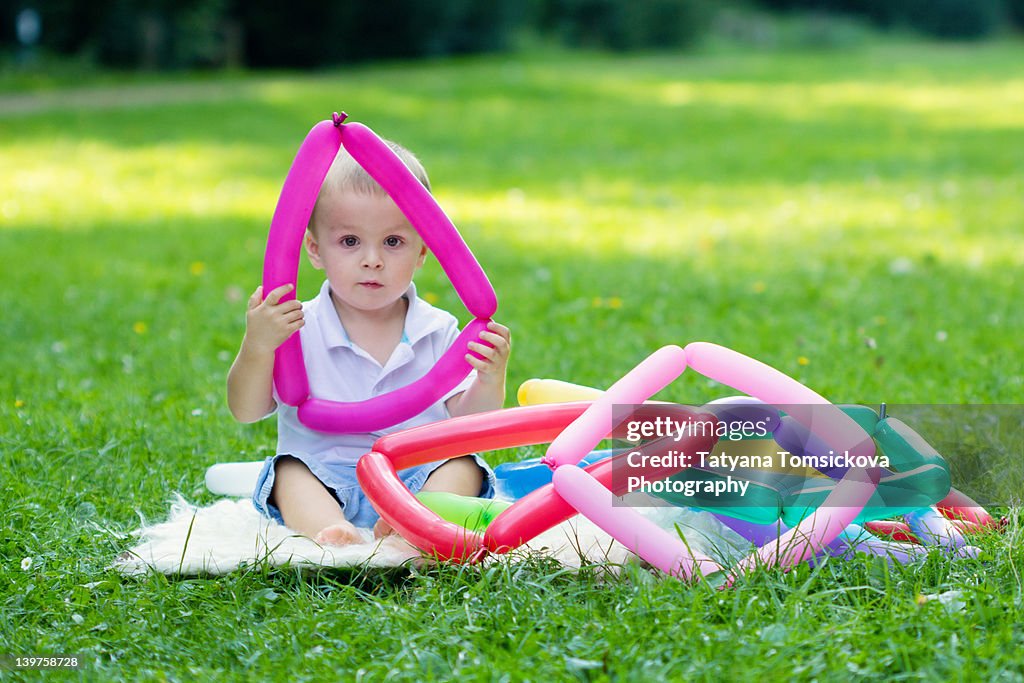 Boy with ballons sitting on grass