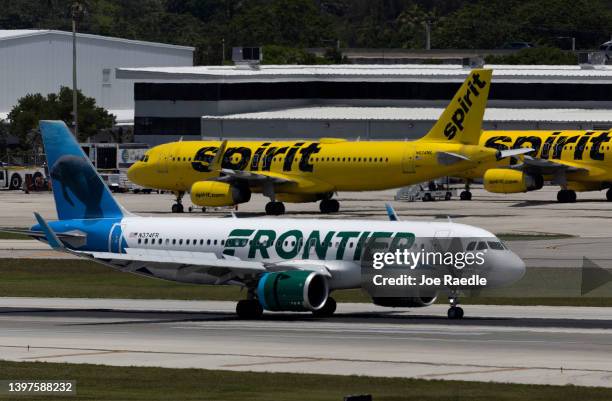 Frontier Airlines plane near a Spirit Airlines plane at the Fort Lauderdale-Hollywood International Airport on May 16, 2022 in Fort Lauderdale,...