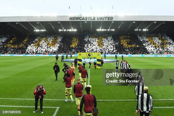 Players of Newcastle United and Arsenal enter the pitch as fans display a tifo in the stands prior to the Premier League match between Newcastle...