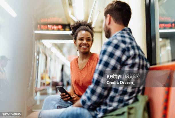 commuting by metro, people talking during the ride and smiling - stranger stock pictures, royalty-free photos & images