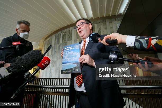 Finance Minister Grant Robertson speaks to media while holding a copy of the Wellbeing Budget 2022 during a photo opportunity at Parliament on May...