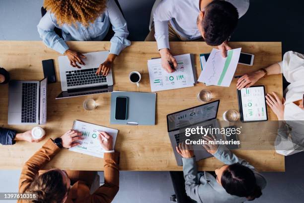 group of businesspeople analyzing business graphs and documents together - office elevated view stock pictures, royalty-free photos & images