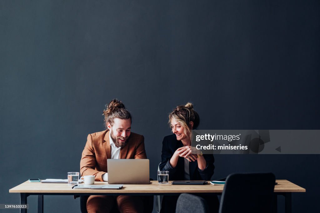 Two Smiling Colleagues Working Together On A New Project