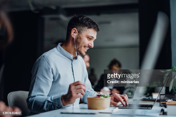 uomo d'affari felice che parla in una videochiamata durante una pausa pranzo in un ufficio - lunch lady foto e immagini stock