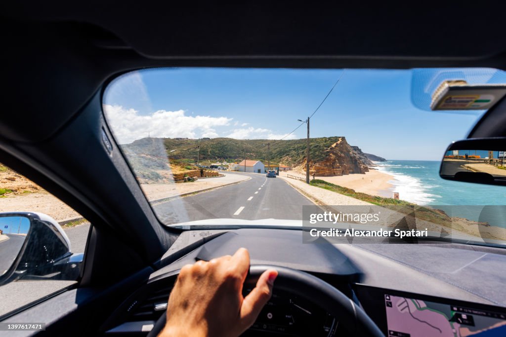 Personal perspective point of view of a man driving along the Atlantic coast in Portugal