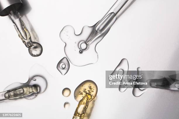 many glass pipettes spilling drops of different moisturizing lotions on luxury silver background. polyglutamic acid is new hyaluronic acid. macro photography - oil macro stock pictures, royalty-free photos & images